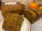 Slice of Pumpkin Gingerbread Loaf on a plate showing toasted pecan pieces - whole loaf in background