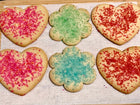 A variety of colorful sugar cookies shaped like hearts and flowers, sprinkled with pink, blue, and red sugar. Available in Berkeley.
