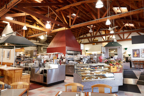 Interior of FATAPPLE'S Restaurant in El Cerrito. High Ceiling with lighting, Bakery Showcase,  Counter and Table seating, front entrance walk way are in the photo