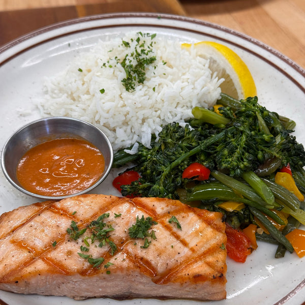 Grilled salmon dinner: 6 oz. grilled salmon filet, basmati rice,  red bell pepper coulis, sautéed vegetables, lemon wedge.  Available in Berkeley.