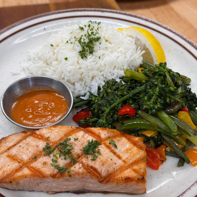 Grilled salmon dinner: 6 oz. grilled salmon filet, basmati rice,  red bell pepper coulis, sautéed vegetables, lemon wedge.  Available in Berkeley.